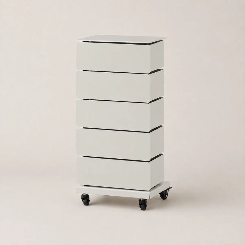 A tall, narrow five-drawer storage cabinet in white with black accents, featuring a flat top and caster wheels at the base, photographed against a plain light beige studio background.