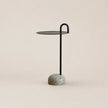 Small side table with a black metal stand and speckled gray base on a beige background