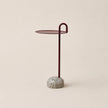 Small side table with a round top and textured base on a beige background