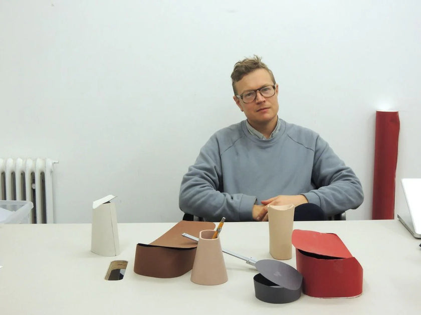 Person sitting at a table with various small, colorful objects on a white background
