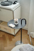 Small round black table with a candle and book on top, next to a record player.