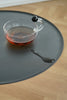 Clear glass with red liquid on a black round side table on a wooden surface
