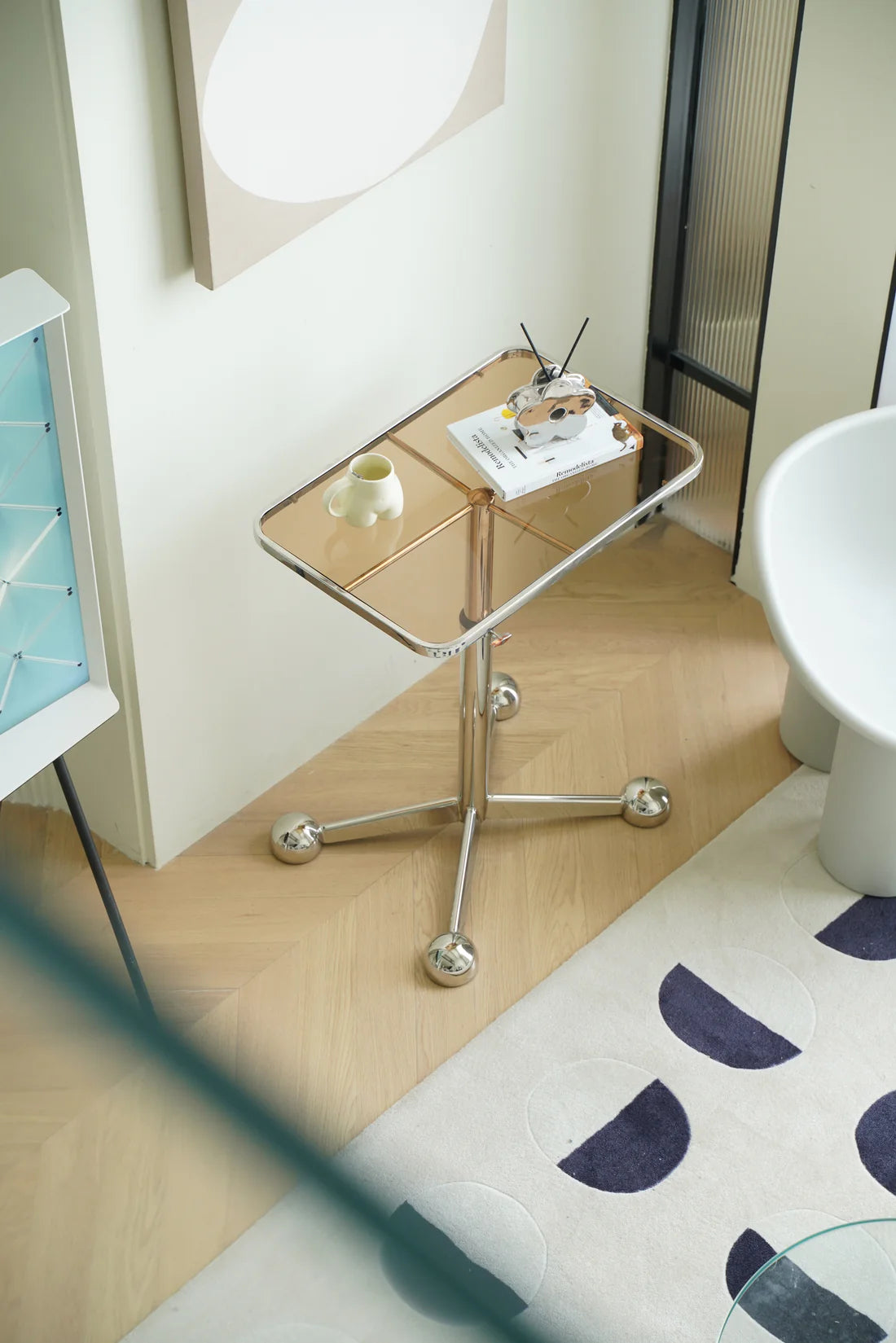 Small glass side tables living room with a metallic base on a wooden floor next to a white cabinet.