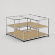 A modular cube storage organizer with a chrome metal frame, clear glass panels on the top, beige cardboard inserts on the middle and bottom shelves, and small black feet at the base, shown on a light gray background.