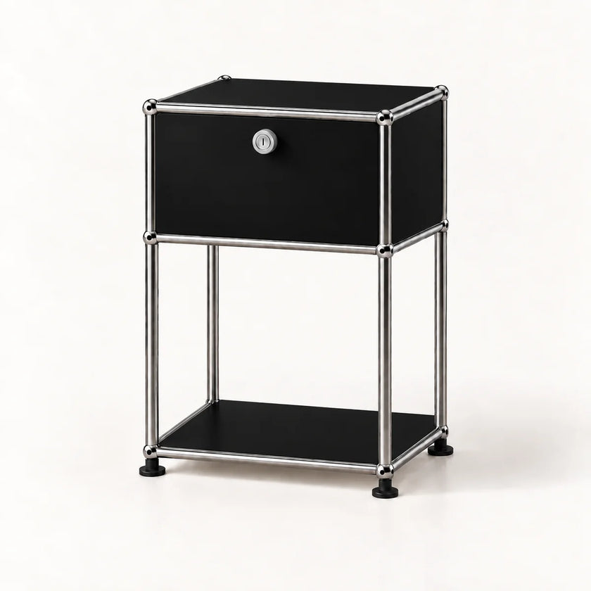 A modern black and chrome storage cabinet with a single drawer, a lock, and an open lower shelf, set against a plain white background.