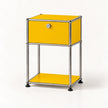 A modern two-tier side table featuring a golden yellow enamel finish and a chrome tubular steel frame, with a single lockable drawer on the top tier and a lower shelf, photographed on a clean white background.