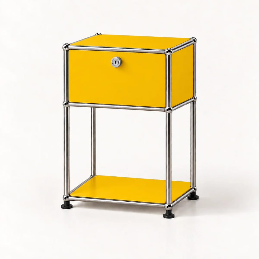 A modern two-tier side table featuring a golden yellow enamel finish and a chrome tubular steel frame, with a single lockable drawer on the top tier and a lower shelf, photographed on a clean white background.