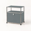 A modern two-tier storage cabinet with a gray faux-leather finish and a chrome tubular metal frame, featuring a single lockable door with a silver keyhole and black rubber feet.