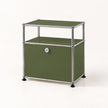 An olive green modular storage cabinet with a chrome metal frame and black feet, featuring two open shelves on top and a single lockable door on the bottom.