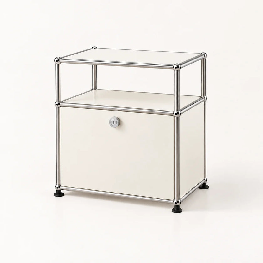 A modern modular storage cabinet with a chrome metal frame, a clear glass top shelf, a cream-colored middle shelf, and a cream lower door with a small round lock. The cabinet stands on black feet against a clean, off-white background.