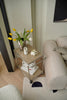 Replica USM modular small stroage sart with flowers and a cup next to a sofa in a living room.