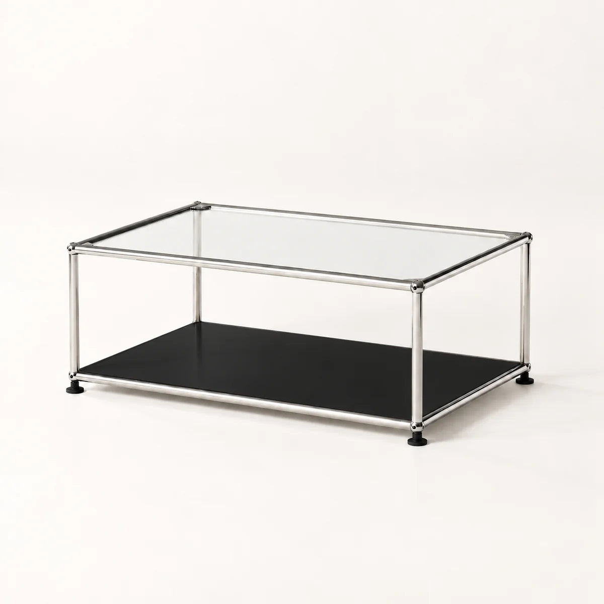 A modern two-tier coffee table with a clear glass top, a black lower shelf, and a slim stainless metal frame with black feet, photographed on a seamless white background.
