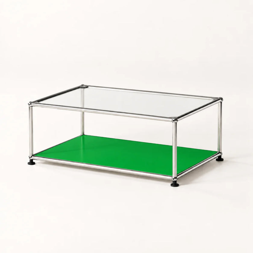 A modern modular coffee table with a clear glass top, a bright green lower shelf, and a stainless metal frame with black feet, shown on a clean white background.