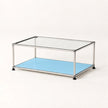 A modern two-tier coffee table with a chrome metal frame, a clear glass top, and a light blue metal lower shelf, shown on a plain off-white background.