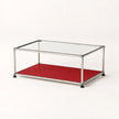 A modern two-tier coffee table with a clear glass top, a stainless metal frame, and a red lower shelf, shown on a clean white background.