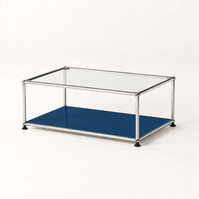 A modern modular coffee table with a clear glass top, a blue lower shelf, and a stainless metal frame with black feet, shown on a clean white background.