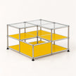 A modular storage organizer made of a chrome metal frame with clear glass panels on top and bright yellow shelves on the sides and bottom, shown on a light cream background.