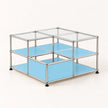 A modular two-tier storage organizer made of a chrome metal frame with light blue metal shelves and clear glass top panels, shown on a clean off-white background.