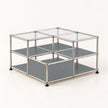 A modular 2-shelf storage organizer with a chrome-finished metal frame, clear glass top panels, and gray shelves, shown on a light beige background.