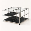 A modular 2-tier organizer cube with a chrome-finished metal frame, clear glass top panels, and black lower shelves, shown on a light off-white background.