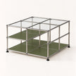 A modular metal storage organizer with a chrome-finished frame, clear glass top panels, and olive green shelves, shown on a clean off-white background.
