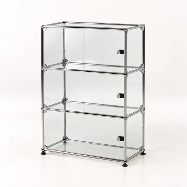A three-tier glass display cabinet with a chrome metal frame and small black feet, shown on a clean white background.