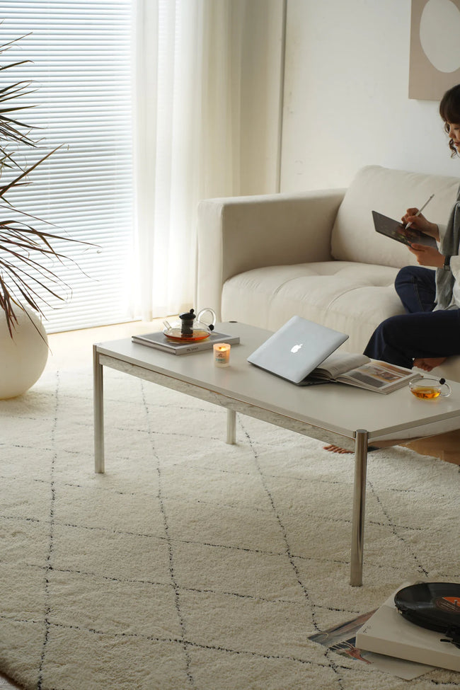 Women sitting on a beige sofa reading a book in a modern living room with a replica USM coffee table.