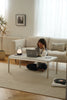 Women sitting on the floor using a replica USM coffee table in a cozy living room.