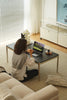 Women sitting on a couch in a living room using a laptop with coffee table.