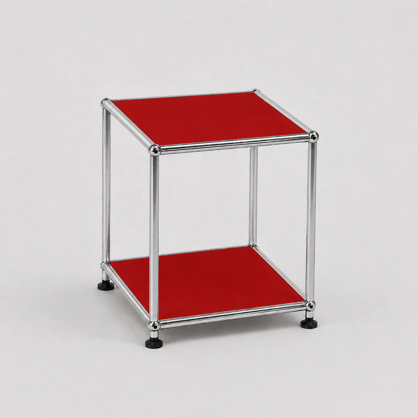 A modern two-tier modular side table with a chrome metal frame and ruby red panel shelves, set against a neutral light gray background.