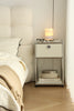 Replica USM modular nightstand next to a bed with a lamp, books, and glasses on top.