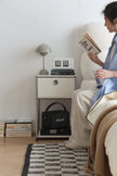 Lady reading a book in a cozy room with a replica USM modular nightstand and lamp.
