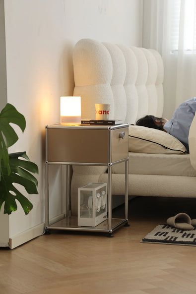 Modern bedroom with a replica USM modular nightstand, lamp, and lady lying in bed.