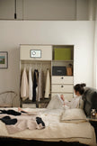 Lady lying on a bed reading a book in a room with a replica USM modular wardrobe and desk.