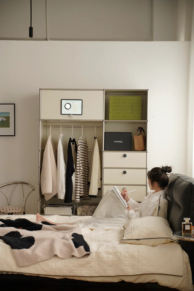 Lady lying on a bed reading a book in a room with a replica USM modular wardrobe and desk.