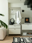Modern interior with a replica USM wardrobe, black bag, white shirt, and decorative items.