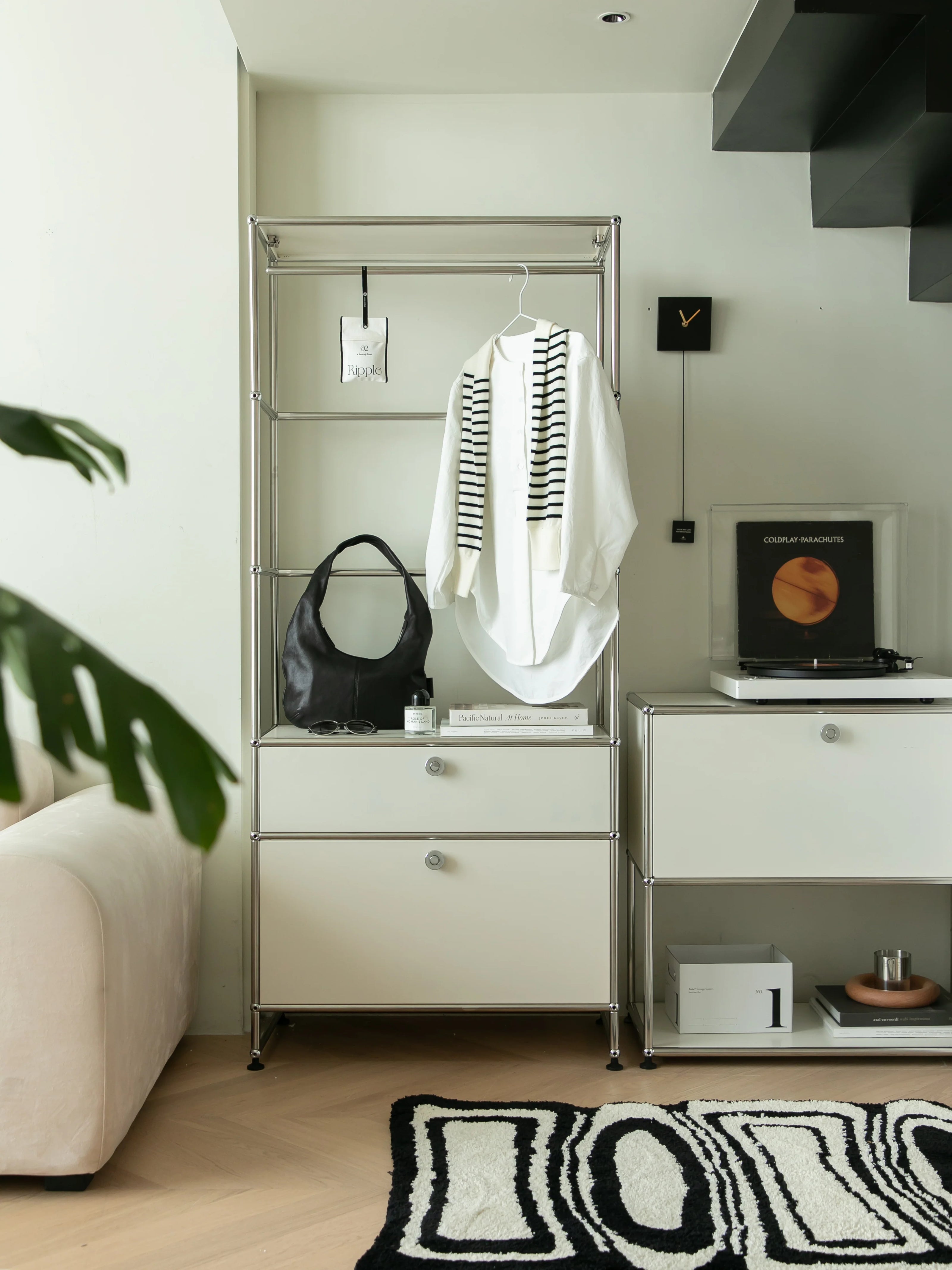 Modern interior with a replica USM wardrobe, black bag, white shirt, and decorative items.