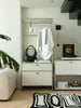 Modern interior with a replica USM wardrobe, black bag, white shirt, and decorative items.