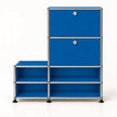 A modular storage cabinet with bright blue metal panels and a silver metal frame, featuring two upper doors with round silver knobs and four lower open shelves, set against a plain white background.