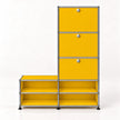 A modular storage cabinet with yellow metal drawer fronts and open shelves, connected by a chrome metal frame with small round silver knobs.