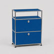 A modular two-drawer storage cabinet with vibrant blue panels and a chrome metal frame, featuring round silver knobs and black feet, set against a light gray background.