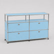 A modular storage cabinet with six drawers in light blue, framed by a chrome metal grid structure with two open top shelves, set against a neutral gray background.
