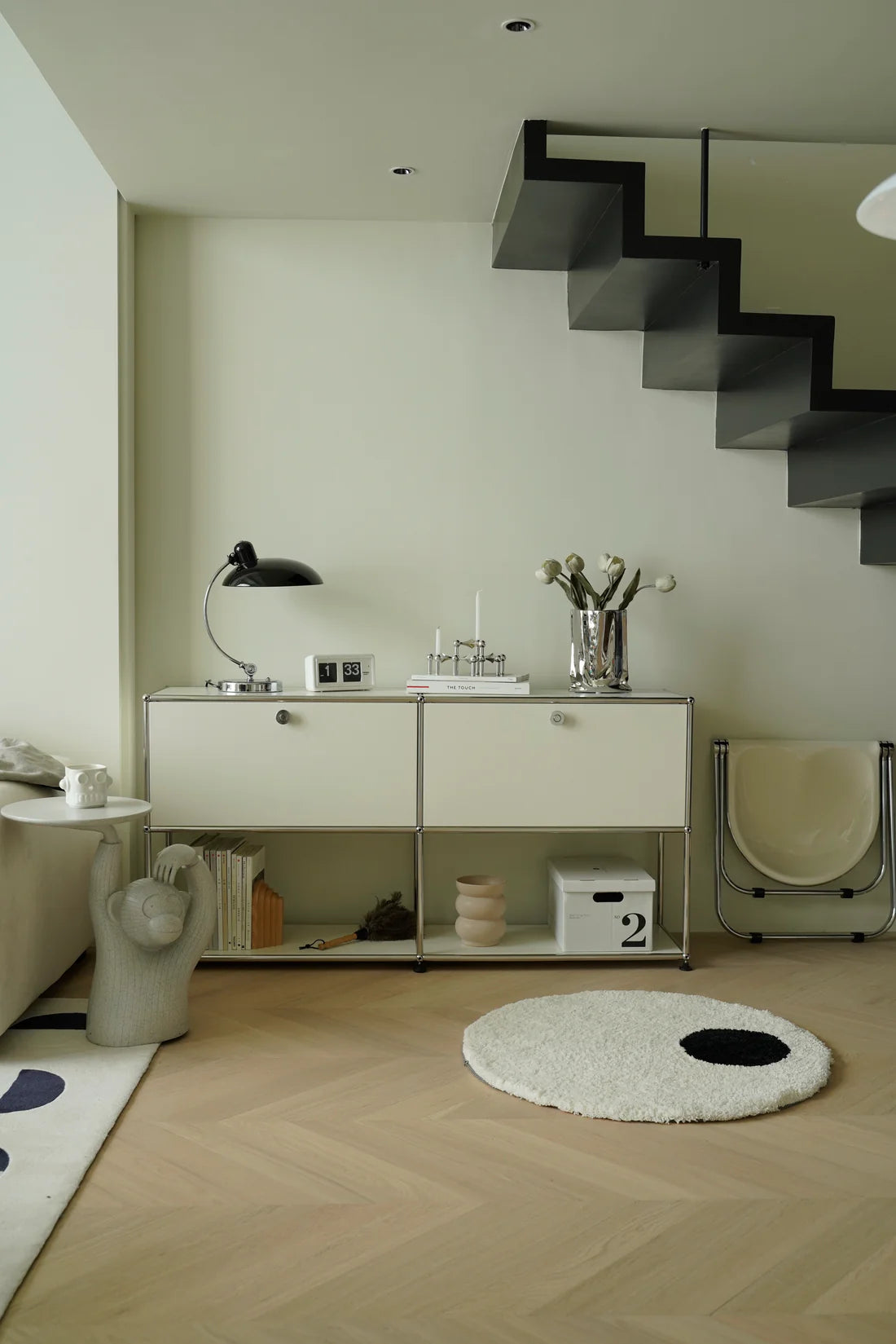 Modern interior with a staircase, white replica USM modular console side table, and decorative items.