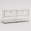 A modern two-drawer storage cabinet with a chrome wire frame, white drawer fronts, round silver knobs, and a lower open shelf, photographed on a light gray studio background.