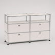 A modular storage cabinet with a chrome metal frame, featuring four drawers arranged in two columns of three, with small round silver knobs and black feet, on a light gray background.