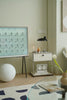 Modern interior with a replica USM modular side table, lamp, and decorative items on a light green wall.