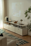 Modern living room with a white replica USM tv stand, sofa, and decorative items.