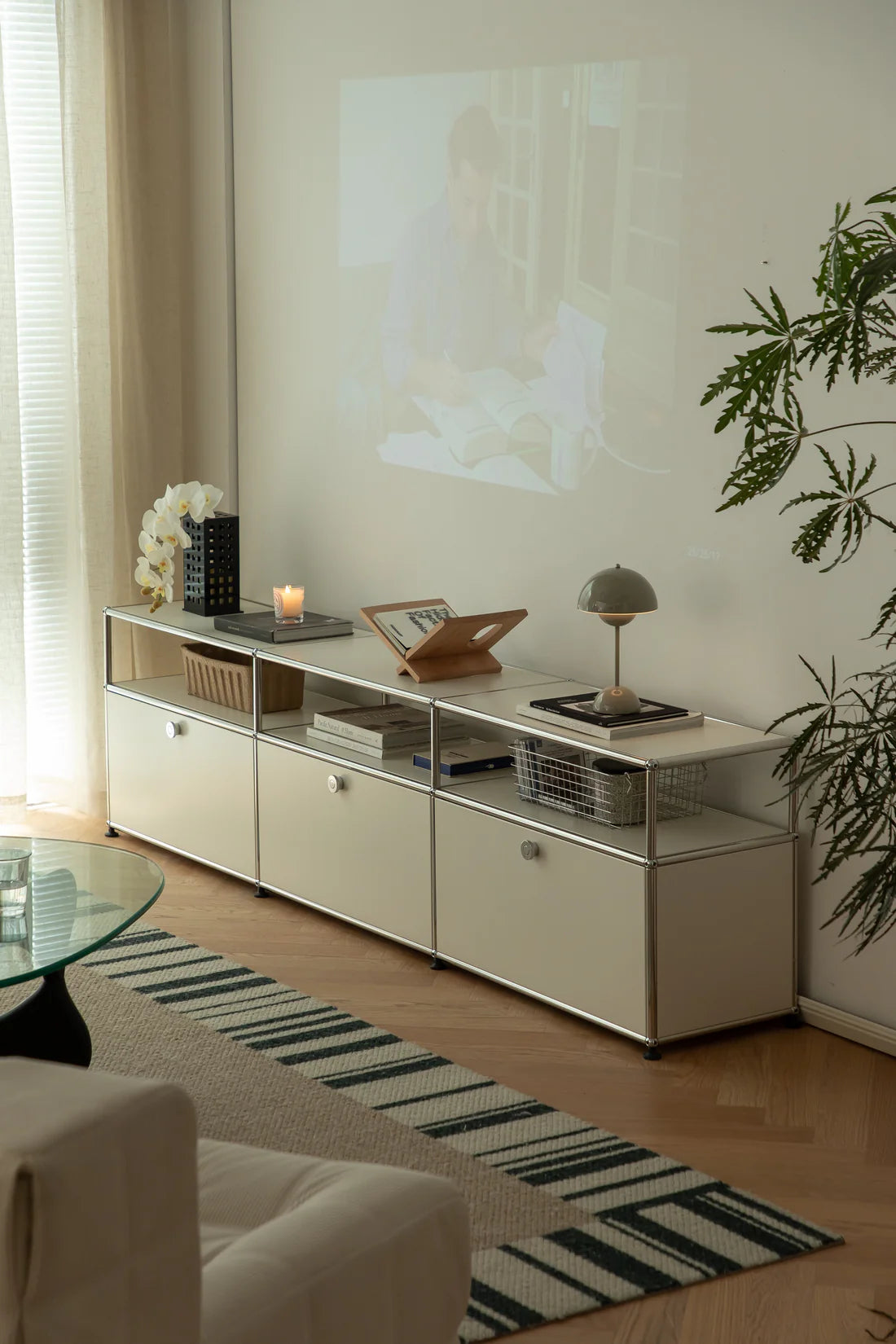 Modern living room with a white replica USM tv stand, sofa, and decorative items.