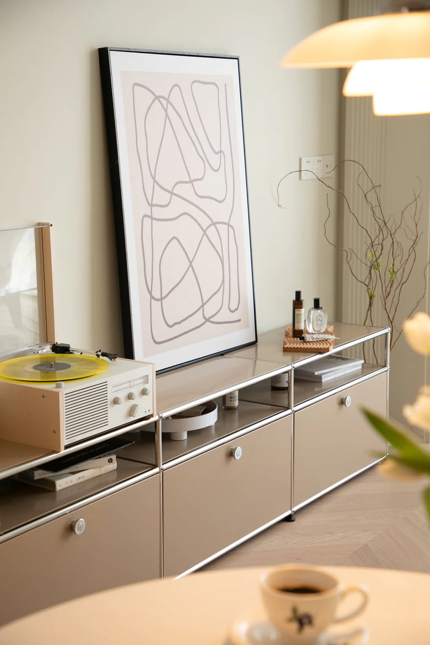 Modern living room with a inspired recreation USM modular television, record player, and abstract art on a light-colored wall.