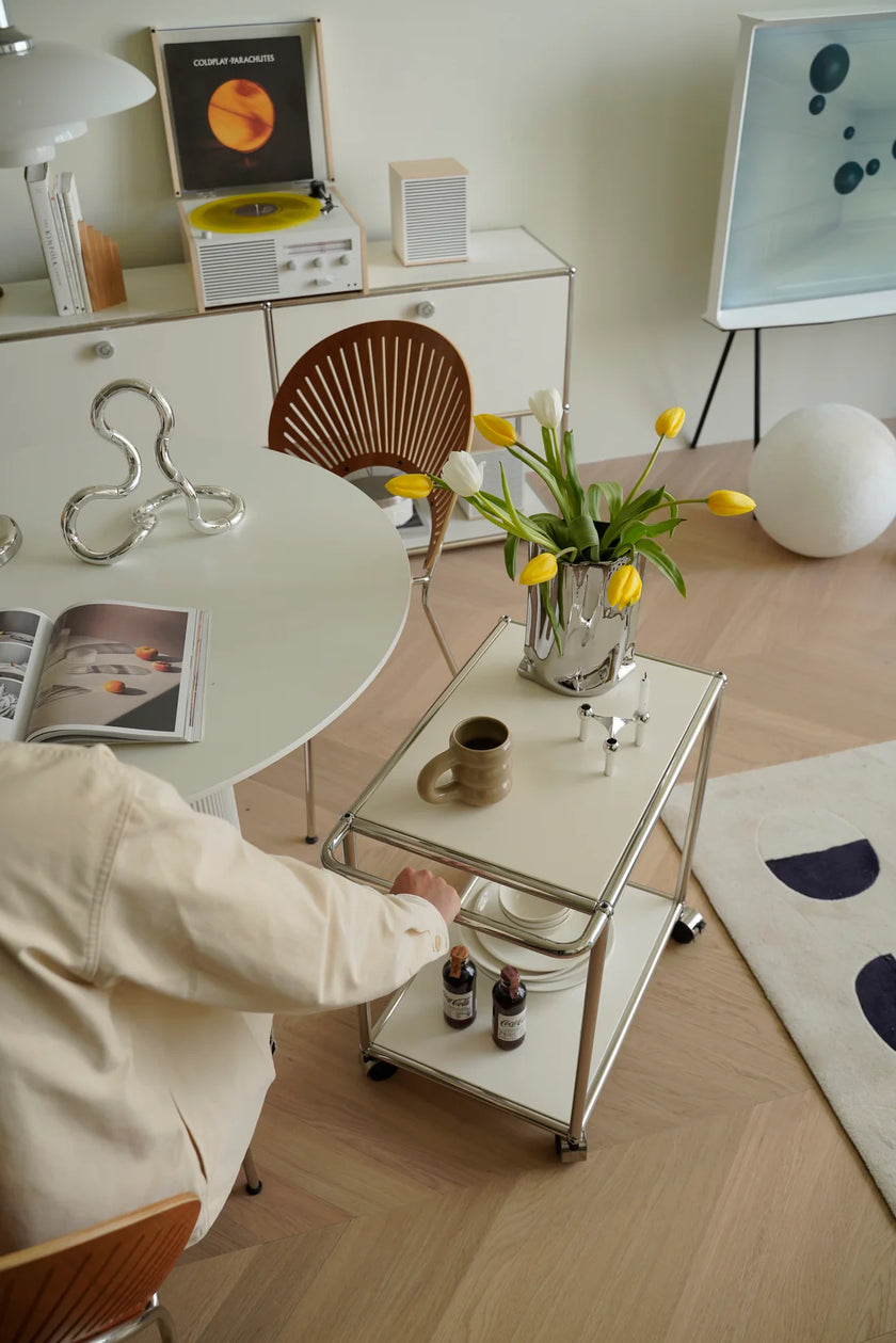 Man interacting with a small inspired recreation USM modular stroage handcart in a modern living room setting.